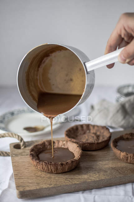 Hand gießt flüssige Schokolade in Kuchen — Stockfoto