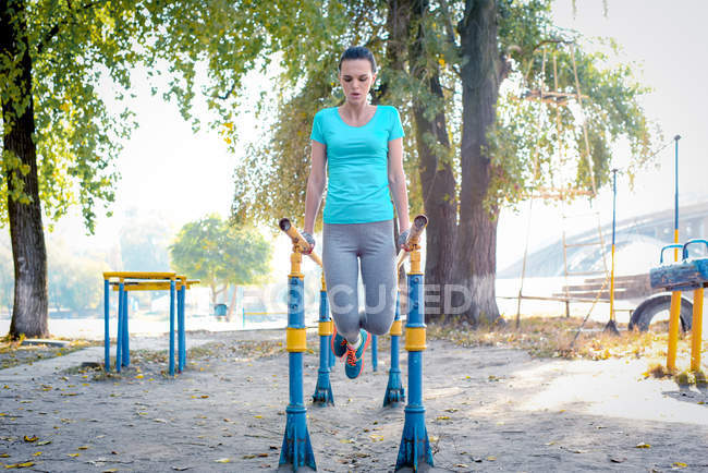 Femme sportive s'exerçant sur des barres parallèles — Photo de stock