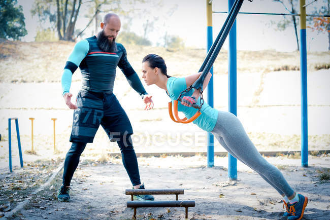 Femme mince avec son entraîneur faisant des exercices — Photo de stock