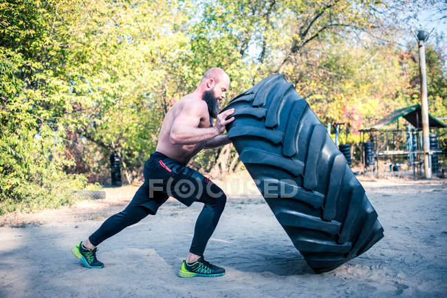 Man lifting a heavy tire — Stock Photo