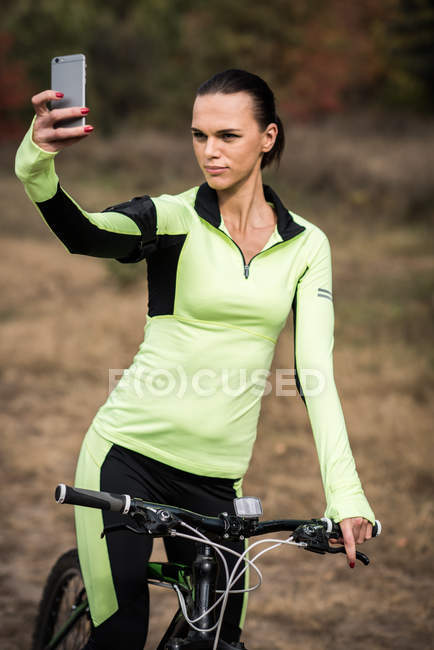 Femme cycliste prenant selfie dans le parc — Photo de stock