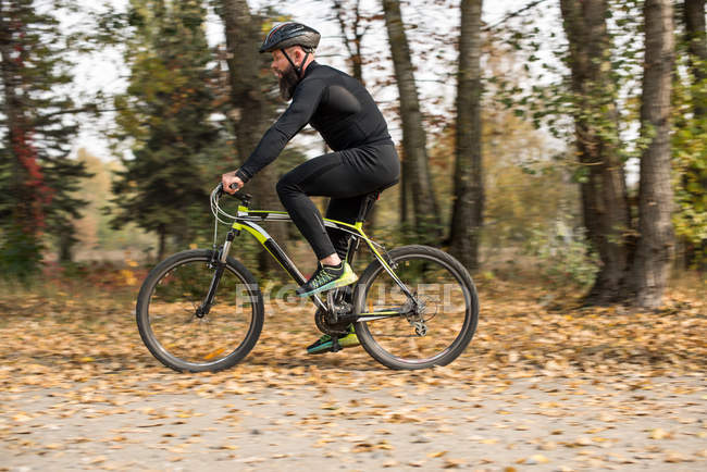 Bearded man cycling in park — Stock Photo