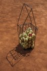 Корзина теннисных мячей, стоящих на поверхности оранжевого корта — стоковое фото