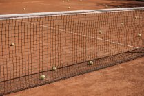 Bolas de tênis bagunçados deitado no campo ao ar livre — Fotografia de Stock
