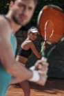 Joven guapo hombre y mujer jugando tenis como equipo - foto de stock
