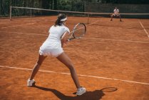 Junge Athletin in Sportbekleidung spielt Tennis mit Mann — Stockfoto