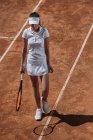 Jovem mulher esportiva com raquete e bola de tênis andando por quadra — Fotografia de Stock