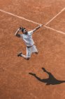Visão de alto ângulo de jovem jogador de tênis fazendo hit no salto — Fotografia de Stock
