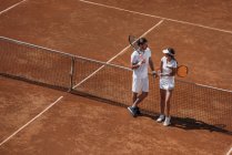 Vue grand angle de jeune bel homme flirtant avec la femme sur le court de tennis — Photo de stock