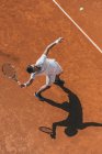 Vista de ángulo alto del hombre haciendo golpe con raqueta de tenis - foto de stock
