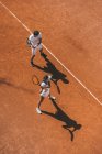 Високий кут зору молода пара грає в теніс як команда — стокове фото