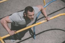 Overhead view of handsome sportsman doing push up at horizontal bar — Stock Photo