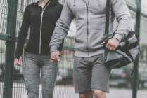 Immagine ritagliata di coppia sportiva che si tiene per mano e cammina al campo sportivo — Foto stock