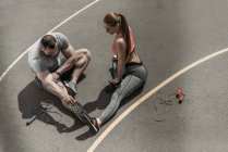 Overhead view of sportswoman and sportsman stretching at sports ground — Stock Photo