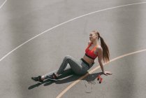 Overhead view of beautiful sportswoman sitting on ground and resting after exercise — Stock Photo