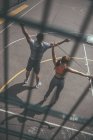 Overhead view through fence of man and woman training with jumping ropes — Stock Photo