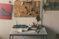 Tisch mit Ledermustern und verschiedenen Werkzeugen mit Schere in der Schuhmacherwerkstatt — Stockfoto