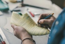 Cropped shot of cobbler holding pencil and working with unfinished footwear workpiece — Stock Photo