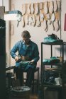 Reifer Schuhmacher arbeitet in Werkstatt mit Schuhwerkstücken — Stockfoto