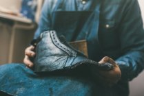 Cropped shot of cobbler holding unfinished leather shoe at workshop — Stock Photo