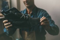 Primo piano colpo di calzolaio guardando stivali di pelle non finiti — Foto stock