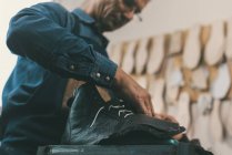 Close-up shot of shoemaker lacing up unfinished leather boot — Stock Photo