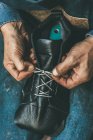 Cropped shot of shoemaker lacing up unfinished leather boot — Stock Photo