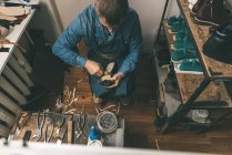 Ansicht des reifen Schuhmachers, der in der Werkstatt mit Werkzeugen arbeitet — Stockfoto