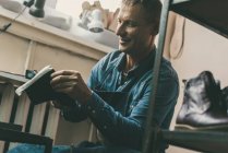 Lächelnder erwachsener Schuhmacher arbeitet in Werkstatt an Paar Schuhen — Stockfoto