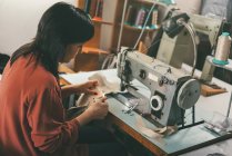 Costureira experiente madura trabalhando com máquina de costura elétrica — Fotografia de Stock