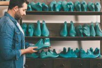 Вид сбоку босоногого сапожника, держащего заготовку обуви в мастерской — стоковое фото