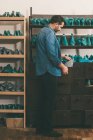 Seitenansicht des Schuhmachers, der Papiere hält, während er in der Werkstatt mit Schuhwerkstücken arbeitet — Stockfoto