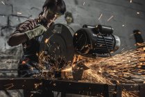 Женщина-сварщик в защитных гуглях с помощью сварочной горелки в мастерской — стоковое фото