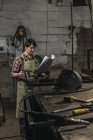 Selective focus of welder with cup of hot drink reading papers in workshop — Stock Photo