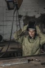 Retrato de trabalhadora manual do sexo feminino decolando capacete protetor após o trabalho em oficina — Fotografia de Stock