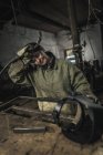Tired female welder holding welding torch in workshop — Stock Photo