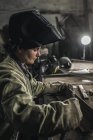 Зосереджений жіночий ручний працівник в захисному одязі в майстерні — стокове фото