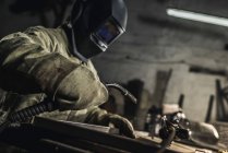 Side view of welder in protective work wear working with welding torch in workshop — Stock Photo