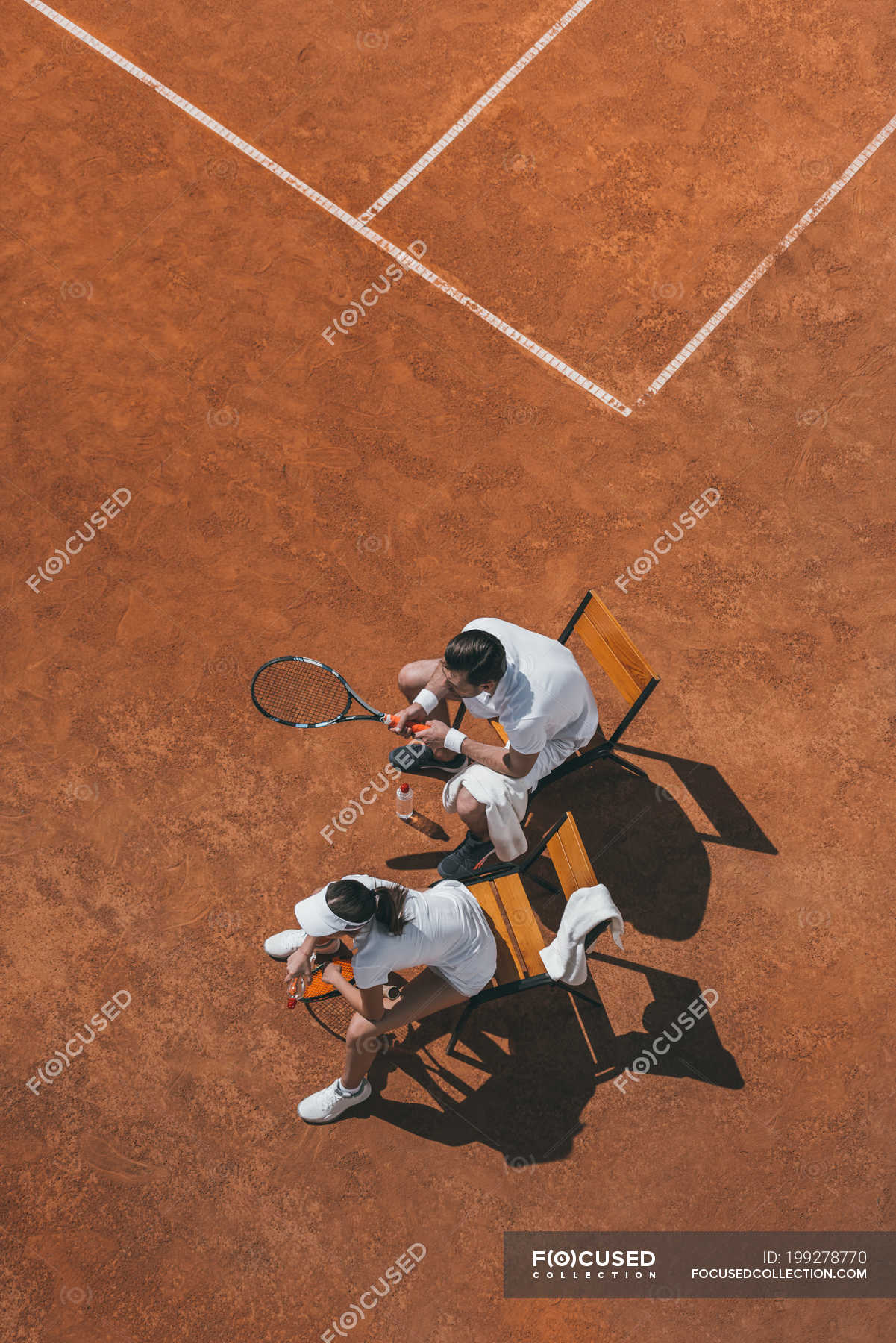 High Angle View Of Young Couple Relaxing On Chairs After Tennis