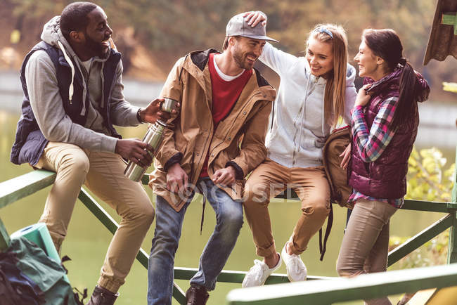 Jóvenes viajeros descansando cerca del río - foto de stock