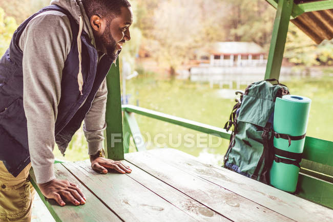 Homme souriant appuyé sur une table en bois — Photo de stock