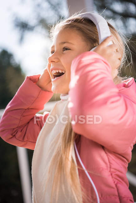 Улыбающаяся маленькая девочка в белых наушниках — стоковое фото
