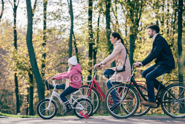 Bicicletas familiares felices en el parque - foto de stock