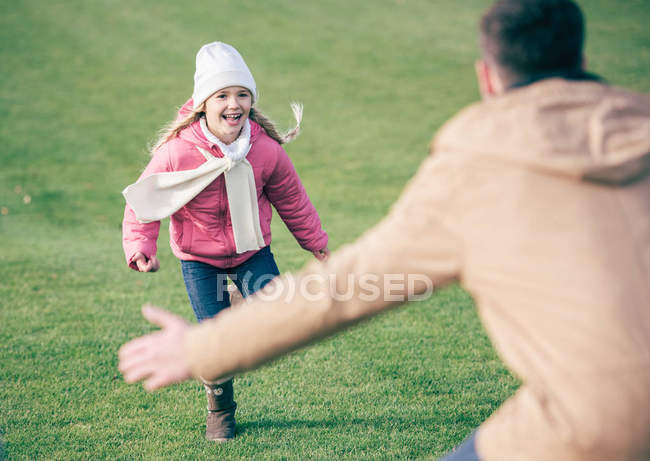 Adorable chica sonriente corriendo a padre - foto de stock