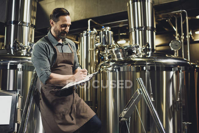 Працівник перевіряє обладнання на пивоварні — стокове фото
