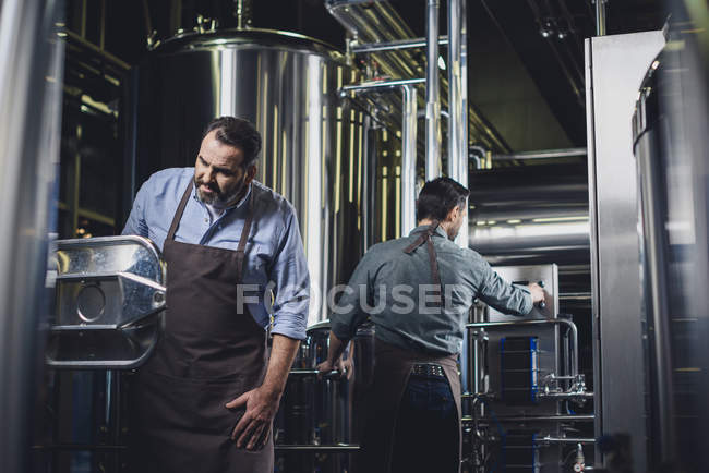 Cerveceros que trabajan con equipos industriales - foto de stock