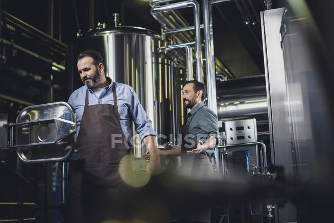 Cervejarias trabalhando com equipamentos industriais — Fotografia de Stock