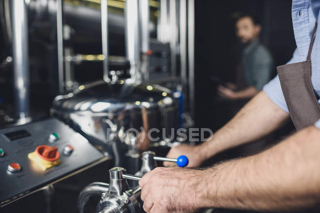 Cervejeiro trabalhando com equipamentos industriais — Fotografia de Stock