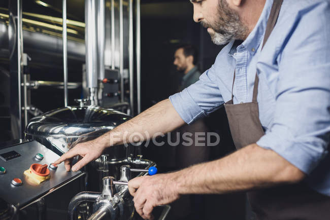 Cervejeiro trabalhando com equipamentos industriais — Fotografia de Stock