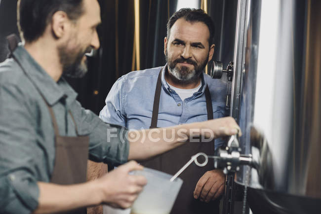 Trabalhador da cervejaria derramando cerveja — Fotografia de Stock